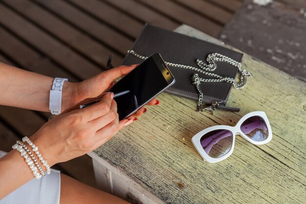 Mani di donna alla moda utilizzando smartphone