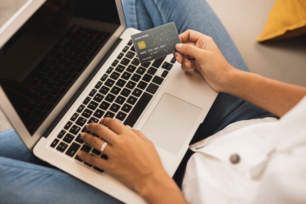 Mani di donna digitando e in possesso di una carta di credito