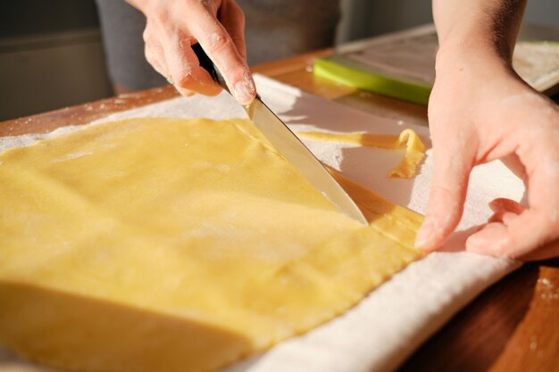 Mani di donna, tagliando la pasta alla luce del sole