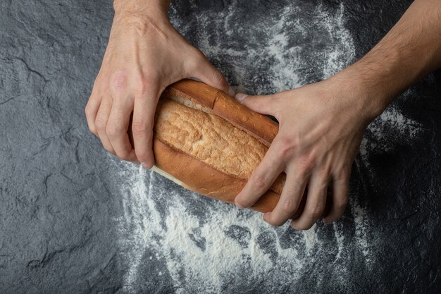 Mani di FeMale che rompono il pane appena sfornato, primo piano.