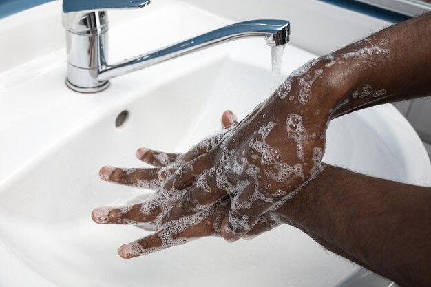 Mani di lavaggio dell'uomo con attenzione nella fine del bagno su. Prevenzione dell'infezione e diffusione del virus dell'influenza