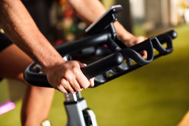 Mani di un uomo di formazione in una palestra facendo ciclo indoor.