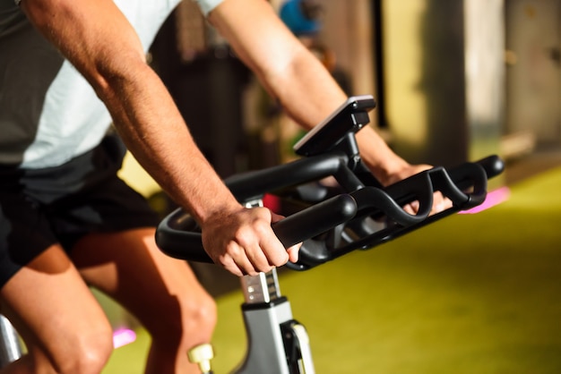 Mani di un uomo di formazione in una palestra facendo ciclo indoor.