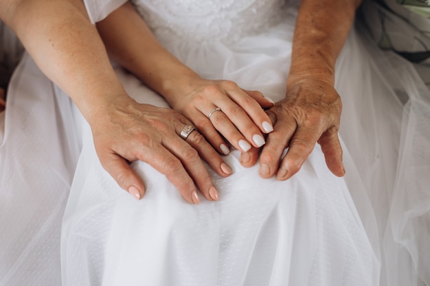 Mani di una giovane sposa e mani dei genitori, diversa generazione, giorno delle nozze