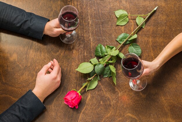 Mani di uomo e donna al tavolo con occhiali e fiori