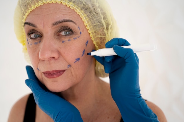 Mani di vista laterale che attingono il viso della donna senior