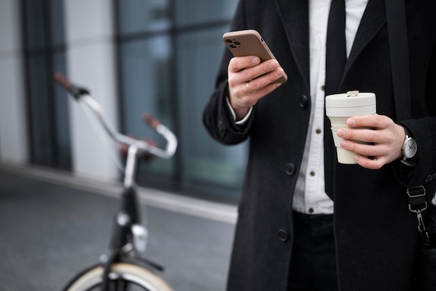 Mani di vista laterale che tengono telefono e caffè