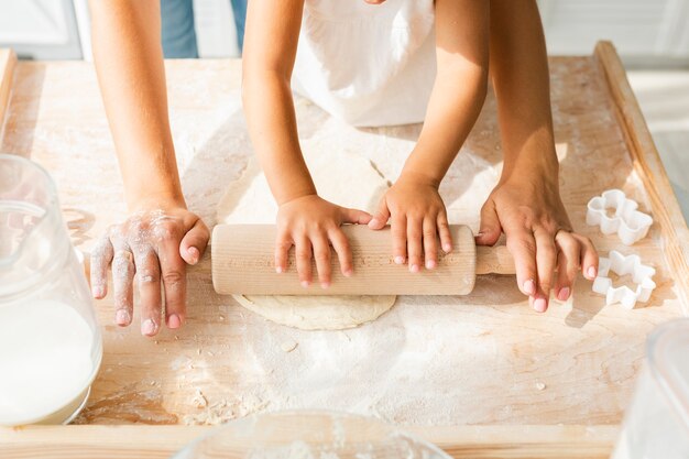 Mani facendo uso del rullo della cucina su pasta