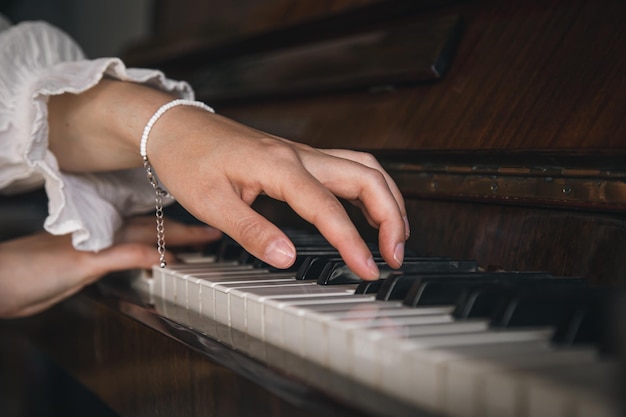 Mani femminili che giocano il vecchio primo piano del pianoforte