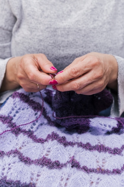 Mani femminili che lavorano a maglia lana viola