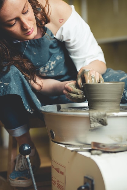Mani femminili che lavorano sulla ruota di ceramica