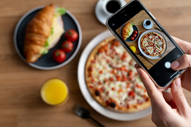 Mani femminili che scattano foto di una pizza a fette e un croissant con formaggio