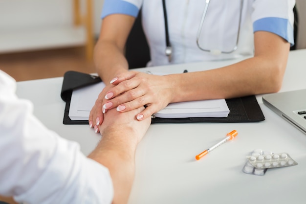 Mani femminili del medico che tengono la mano paziente