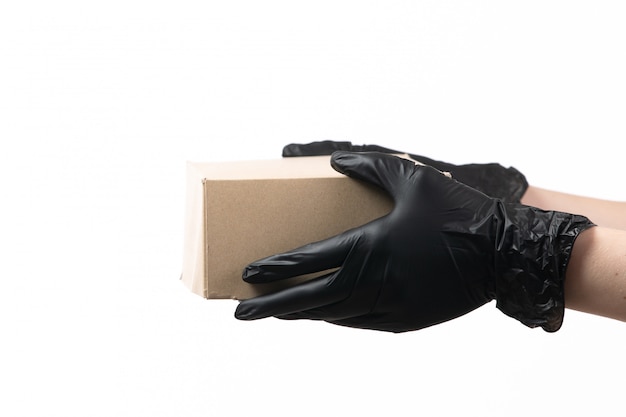 Mani femminili di una vista frontale in guanti neri che tengono il pacchetto di consegna su bianco