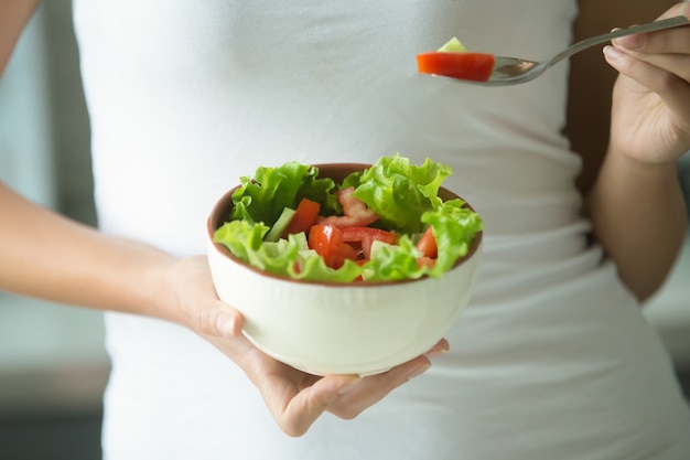 Mani femminili in possesso di una ciotola di insalata verde