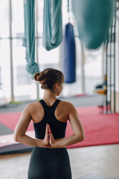 Mani incrociate dietro la schiena, ragazza in palestra durante la lezione di yoga