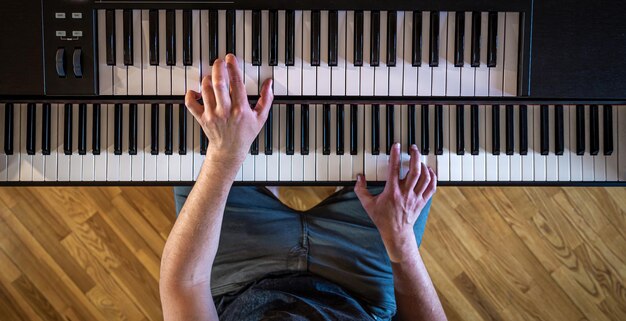 Mani maschili sulla vista dall'alto dei tasti del pianoforte