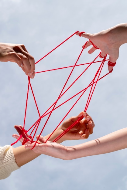 Mani umane collegate con filo rosso