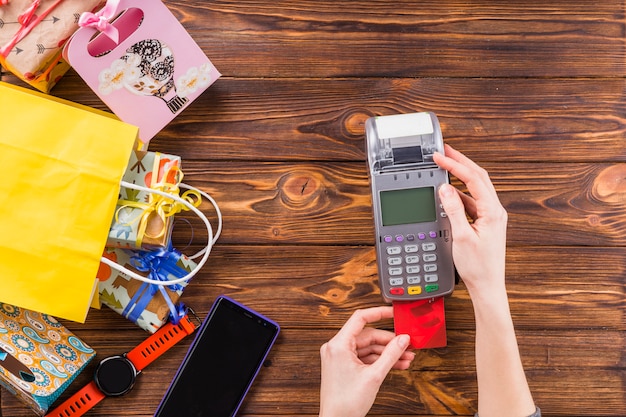 Mani umane facendo uso della carta strisciante della carta di credito per il pagamento in deposito