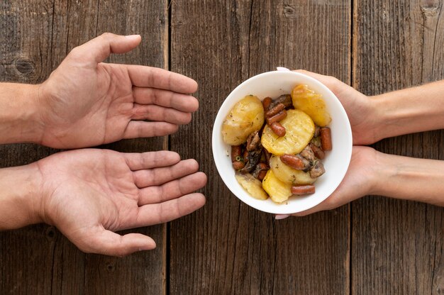 Mano che dà la ciotola del cibo donata alla persona bisognosa