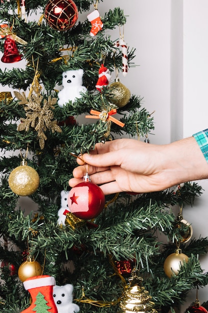 Mano che decorano albero di natale