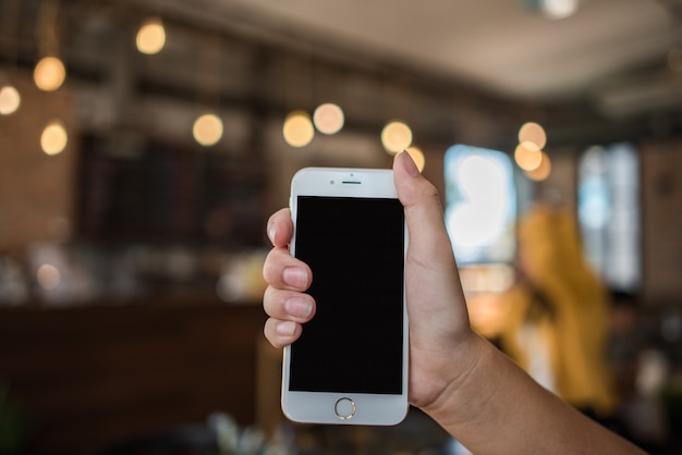 Mano che tiene il cellulare bianco con schermo nero vuoto