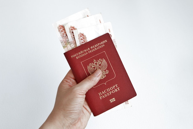 Mano che tiene il passaporto russo con 5000 rubli banconote