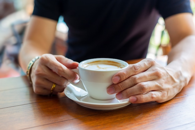 Mano che tiene la tazza di caffè caldo