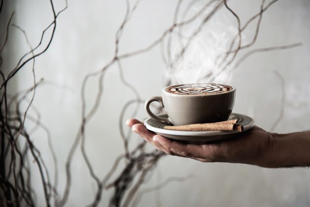 Mano che tiene tazza di caffè caldo