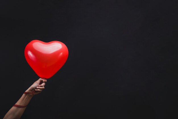 Mano che tiene un palloncino a forma di cuore