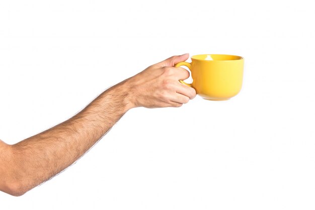 Mano che tiene una tazza di caffè giallo sopra bianco