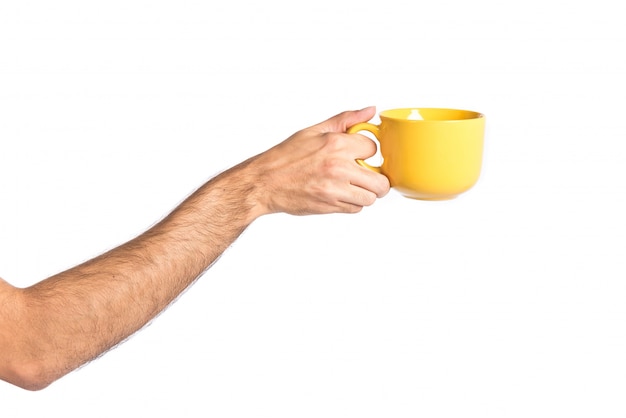 Mano che tiene una tazza di caffè giallo sopra bianco