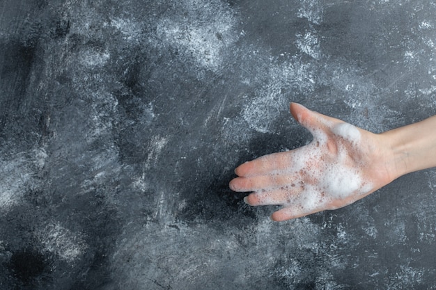 Mano con bolle di sapone che mostra la mano sul marmo.