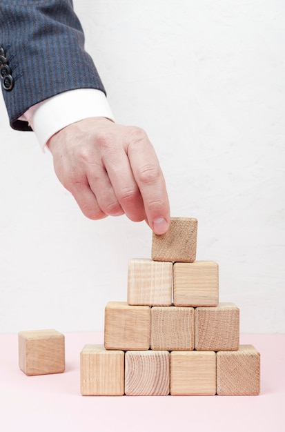 Mano creando piramide da cubi di legno