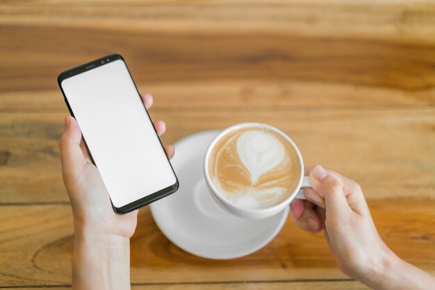 Mano d&#39;affari con il telefono cellulare e il latte art coffee.