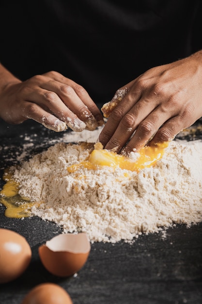 Mano del primo piano che mescola farina e tuorlo