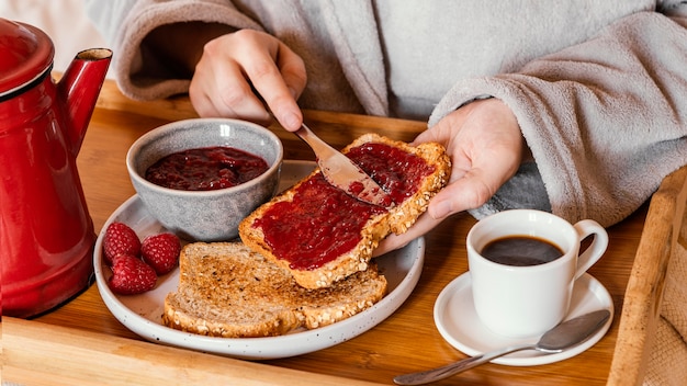 Mano del primo piano che mette marmellata sul pane