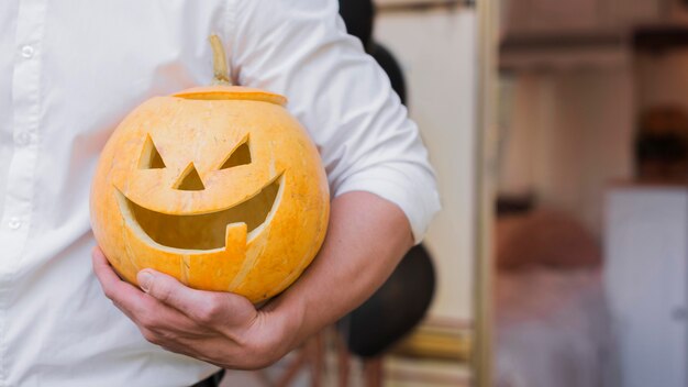 Mano del primo piano che tiene la zucca intagliata