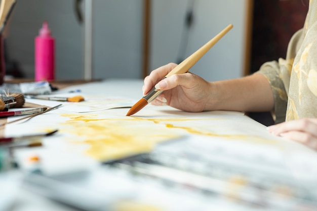 Mano del primo piano con la pittura della spazzola