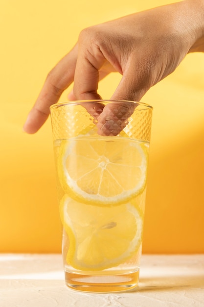 Mano del primo piano con un bicchiere di limonata fresca