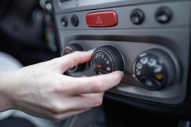 Mano della donna che accende il sistema di aria condizionata dell'automobile condizionatore d'aria dell'automobile sul pulsante di spegnimento vista ravvicinata