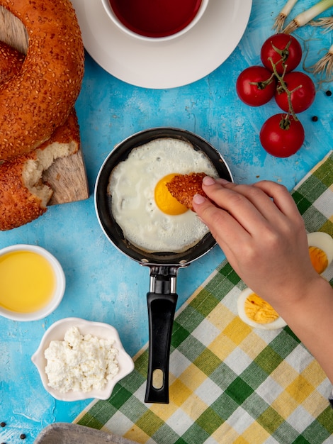 mano della donna che mangia pane con l'uovo fritto