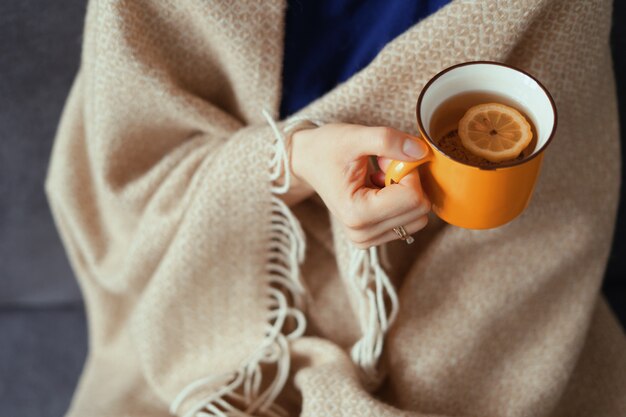 Mano della donna che tiene tazza di tè al limone