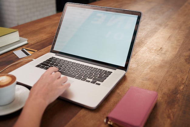 Mano della donna irriconoscibile che lavora al computer portatile in caffè