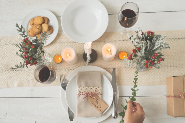 Mano della donna irriconoscibile che mette ramo verde sulla tavola di cena di Natale