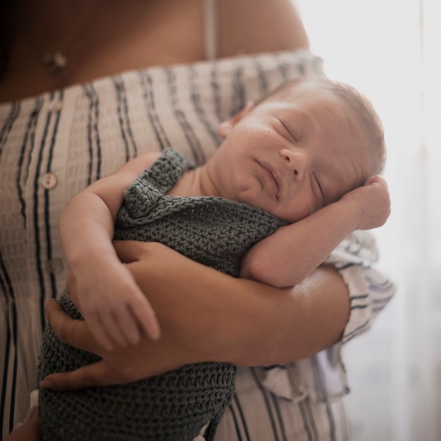 Mano della madre che tiene piccolo bambino sveglio