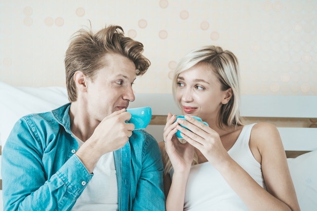 Mano felice delle coppie che tiene tazza e che beve caffè di mattina