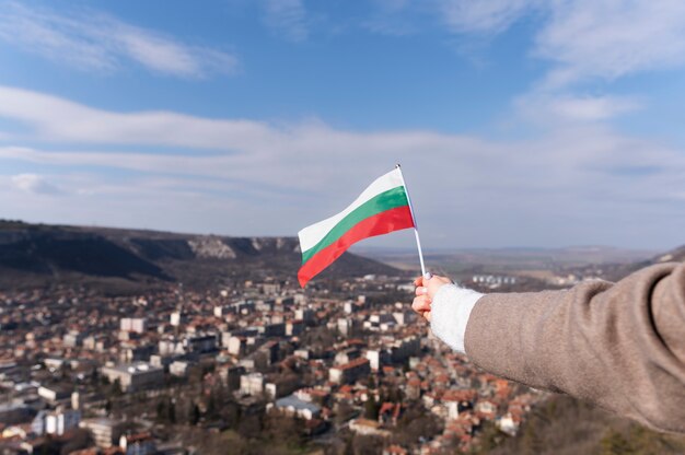 Mano femminile che tiene la bandiera del tessuto della Bulgaria