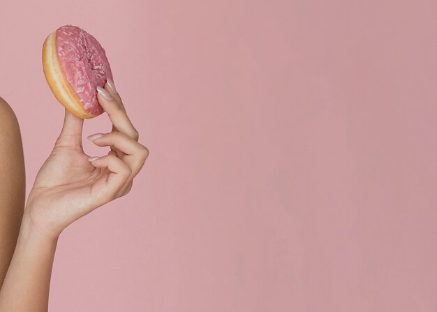 Mano femminile che tiene una ciambella appetitosa