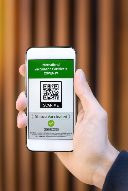 Mano maschile che tiene uno smartphone con codice QR del certificato di vaccinazione internazionale COVID-19